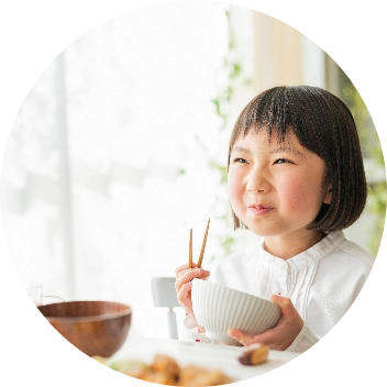 小さな女の子がご飯を食べて笑顔になっている